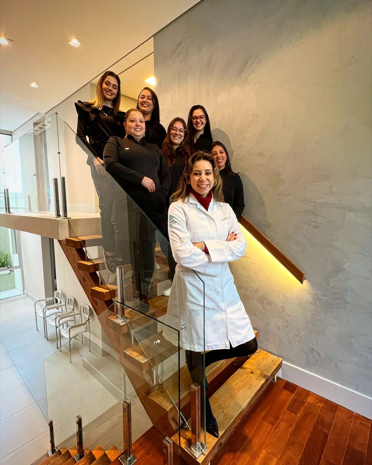 A Dra. Valéria com a equipe na escada da clínica